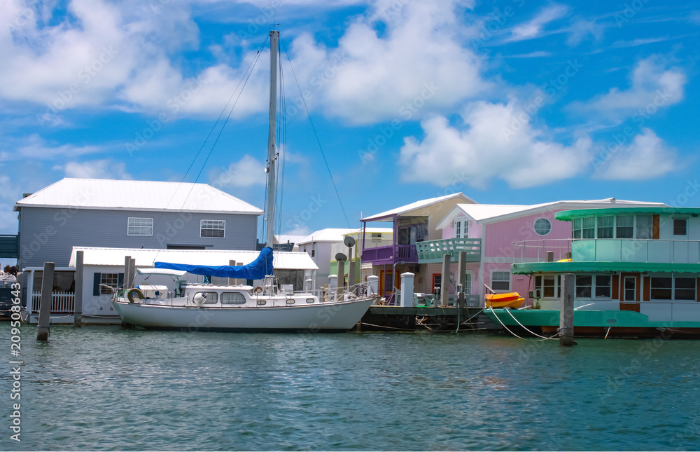 Fototapeta premium A sailboat moored near colorful houseboats at a marina near Key West.