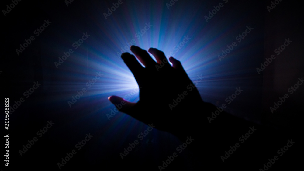 dark hand in mystery scene , projector light in a smoke background .