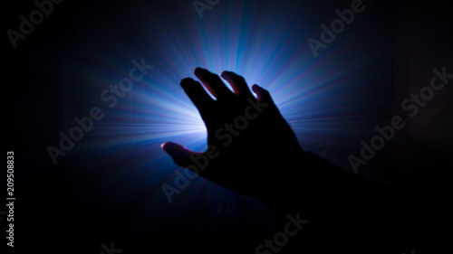 dark hand in mystery scene , projector light in a smoke background .