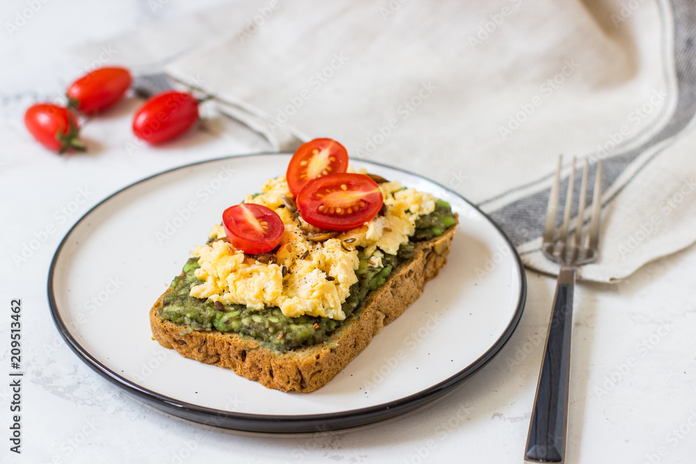 Scrambled eggs on whole wheat bread with avocado and cherry tomatoes Scrambled eggs on whole wheat bread with avocado and cherry tomatoes