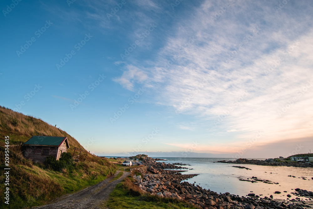 Beautiful scene of a landscape in a rural area beside the ocean at sunset. Cosy Nook, New Zealand. Beautiful scene of a landscape in a rural area beside the ocean at sunset. Cosy Nook, New Zealand.
