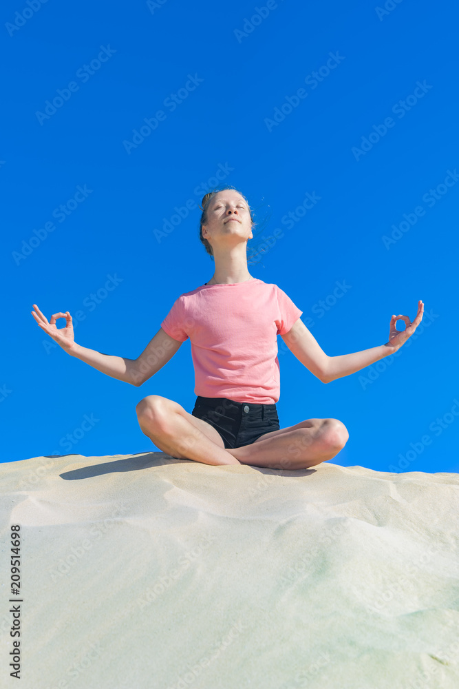 ein junges Mädchen macht Yoga Übungen / Meditation in freier Natur, vor blauem Himmel ein junges Mädchen macht Yoga Übungen / Meditation in freier Natur, vor blauem Himmel