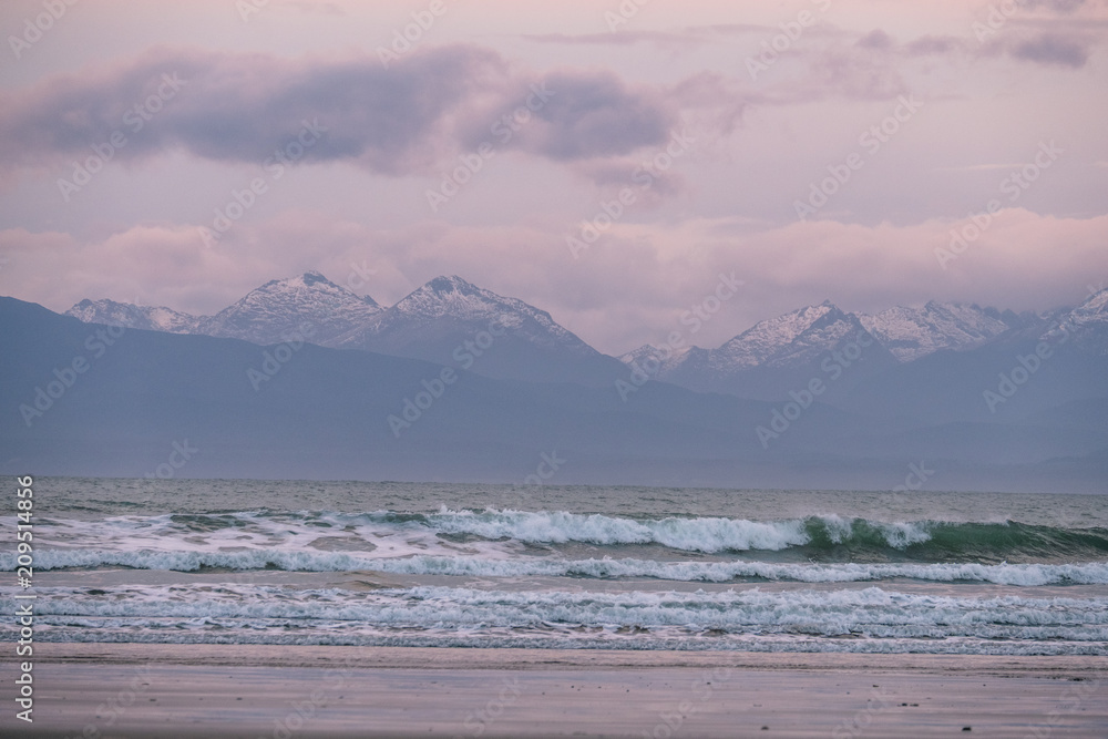 Beautiful scene of the beach with snow mountain at dusk.