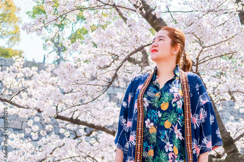 Pretty Asian woman in  Sakura Nishinomaru Garden. The cherry blossom park at Osaka Japanese Castle Area in Osaka, Japan, Asia. photo