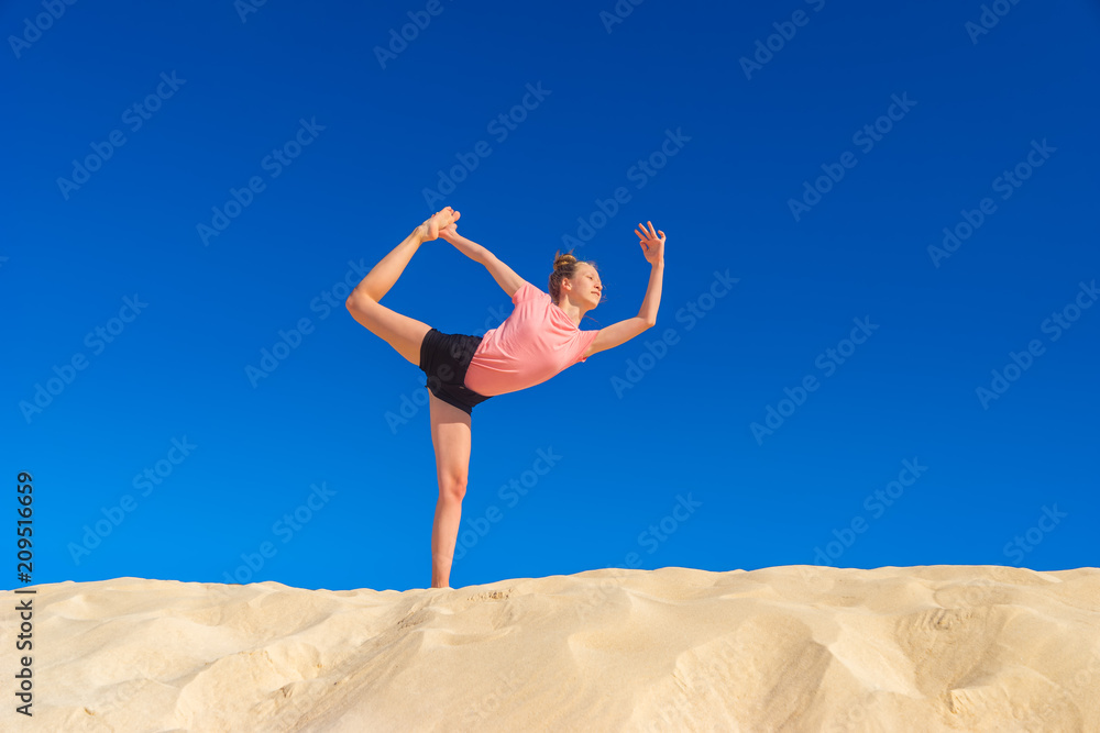 ein junges Mädchen macht Dehungsübungen / Meditation in freier Natur, vor blauem Himmel ein junges Mädchen macht Dehungsübungen / Meditation in freier Natur, vor blauem Himmel