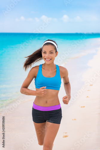 Fitness girl running on beach in fashion activewear clothes. happy