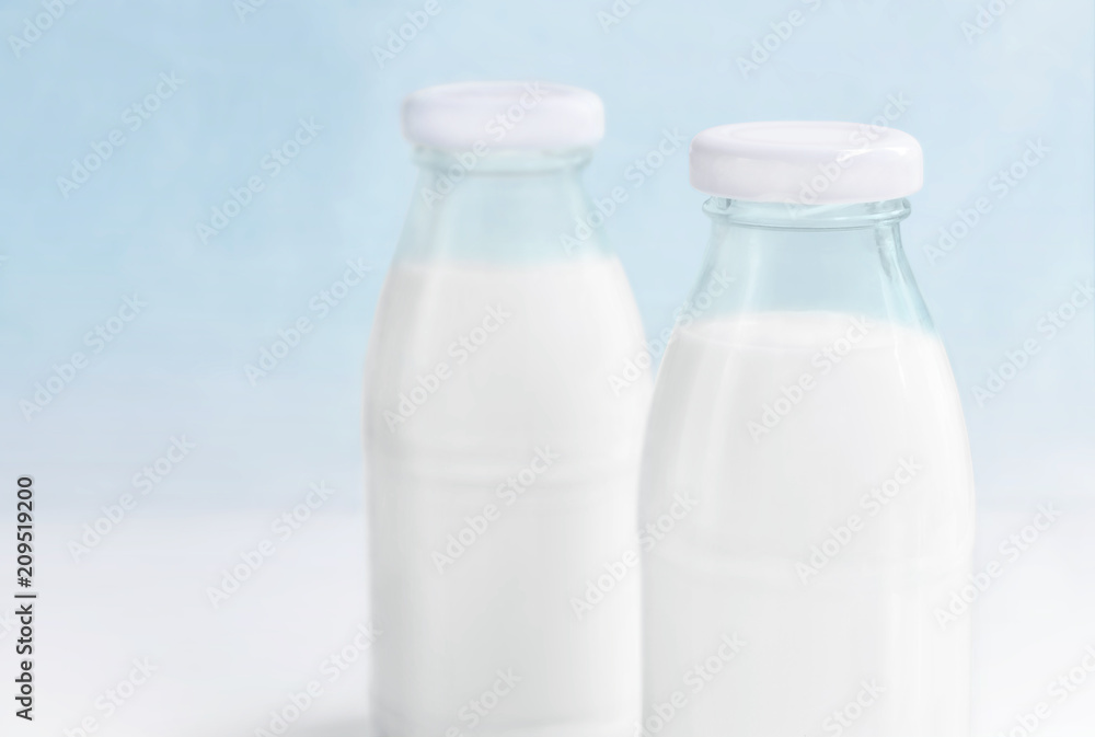 Two glass bottle of milk on the white table on a blue background. with copy space for text. Two glass bottle of milk on the white table on a blue background. with copy space for text.