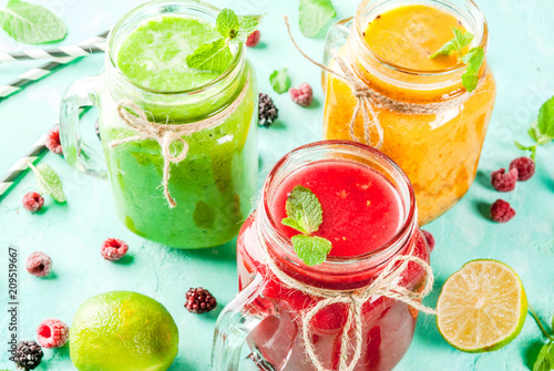 Healthy fresh fruit and veggie smoothies with ingredients on light blue concrete table, copy space