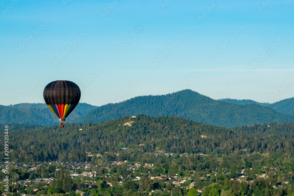 Naklejka premium Hot air balloon over wooded hillsides