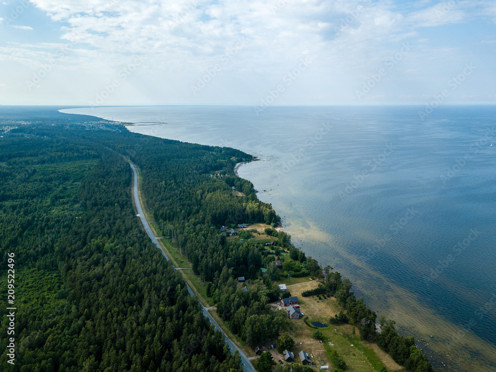 drone image. aerial view of Baltic sea shore with rocks and forest on land and highway near water