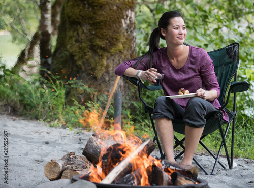 Asian woman drinking wine near camp fire © Mat Hayward