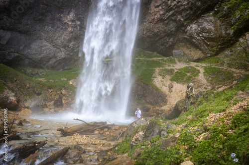 European man with beard is doing waterfall-meditation while standing under big waterfall in austria  wildensteiner waterfall