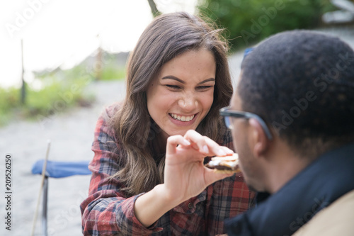 Happy couple feeding each other s'mores at camp site