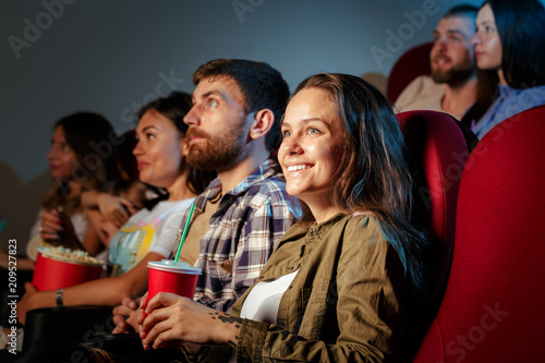 Group of friends sitting in movie theater with popcorn and drinks