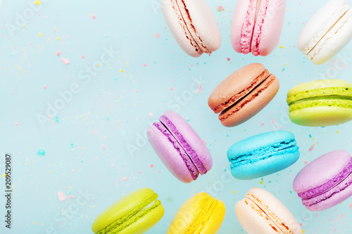 Flying cake macaron or macaroon on blue pastel background. Colorful almond cookies on dessert.