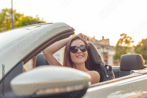 Beautiful girl in the  convertible cabrio car on a sunny day in a city