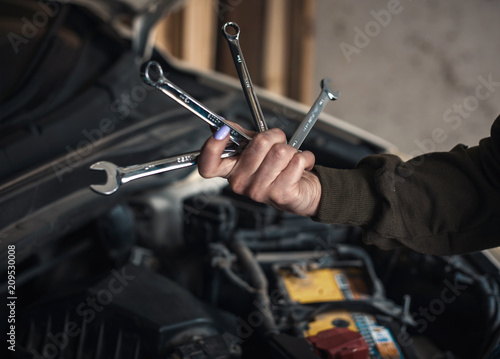 A beautiful girl repairs and maintains a car in the garage. Women in Men's Professions
