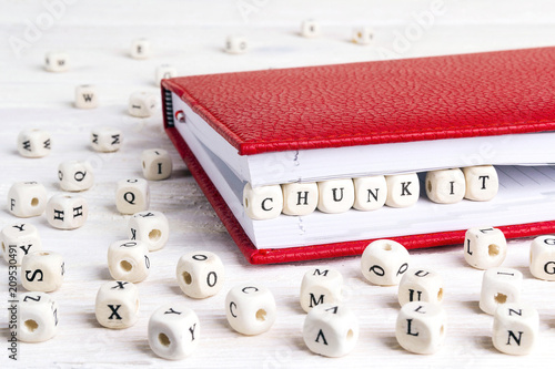 Phrase Chunk it written in wooden blocks in red notebook on white wooden table.