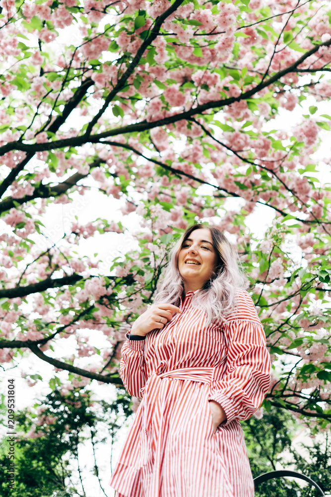 Beautiful Young Woman Enjoying Sunny Day in Park during Cherry Blossom Season