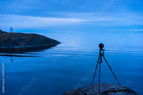 The camera stands on a tripod. Small islands. Rocky shore. Photography of wild nature. Protocols between the islands. Journey to the wild.