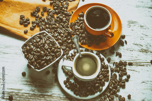 Coffee in a white and orange cup. Espresso with  milk. Old white oak tree. Still life in side light with retro analogue filter with vintage. Coffee beans on the table. Orange tablecloth on table.   photo