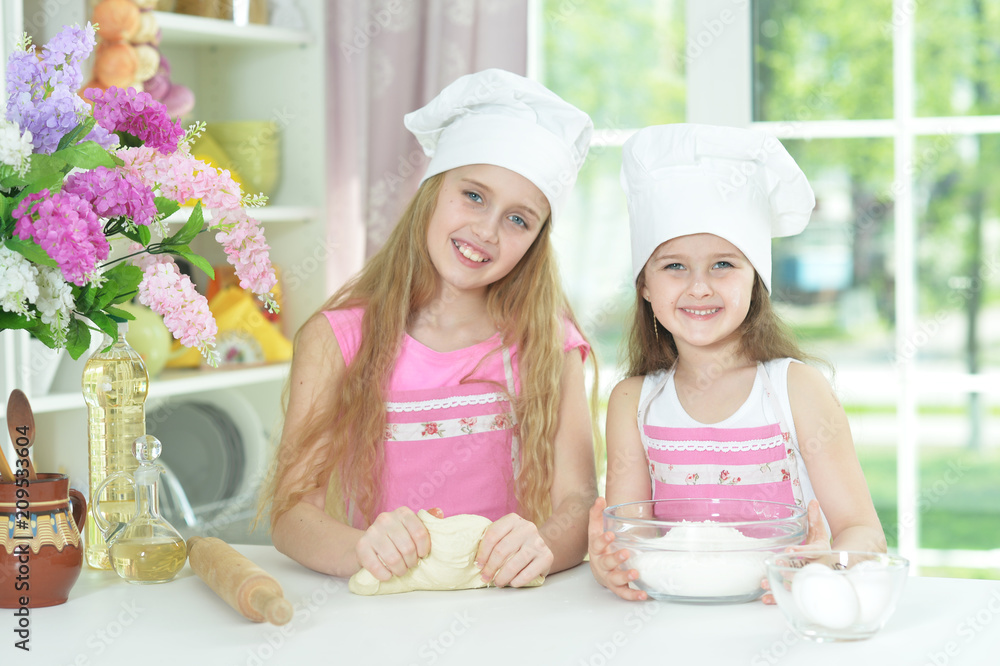 Cute little girls in chefs hats making dough Cute little girls in chefs hats making dough