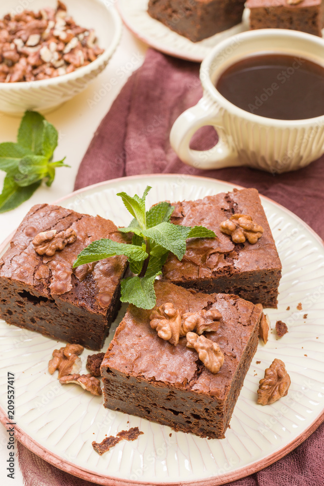 Brownie sweet chocolate dessert with walnuts and meant leaves on craft plate and cup of black coffee. Brownie sweet chocolate dessert with walnuts and meant leaves on craft plate and cup of black coffee.