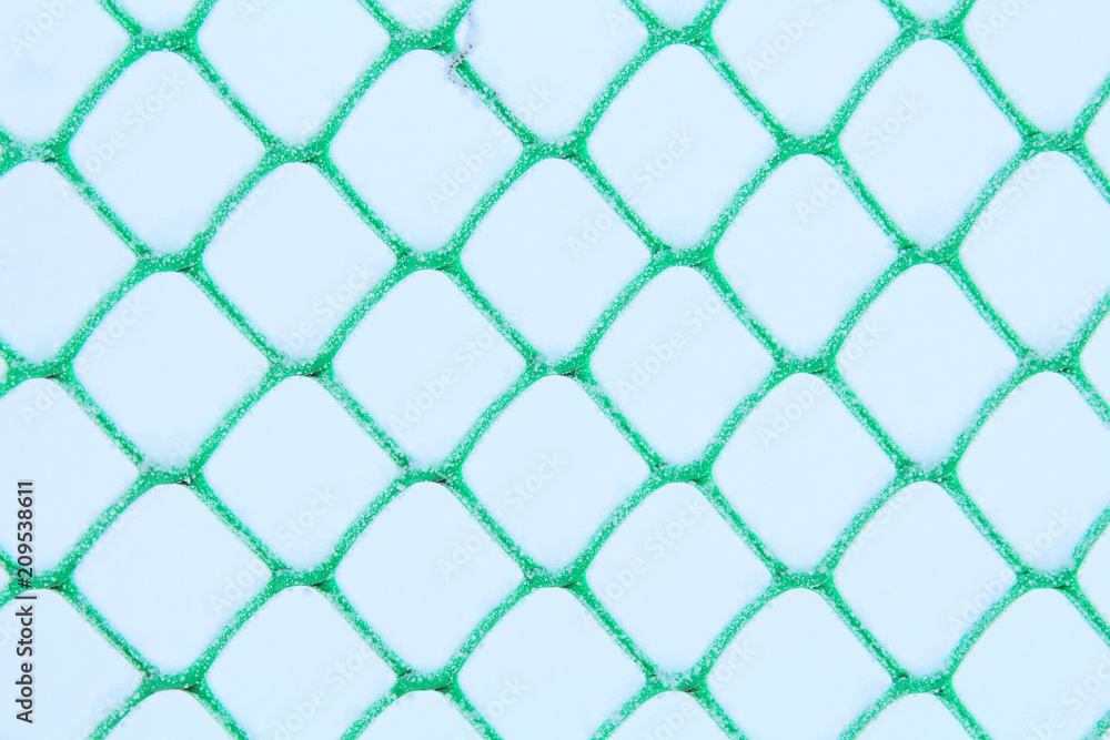 Fototapeta premium Plastic mesh covered with snow. Fence. Close-up. Background. Texture.