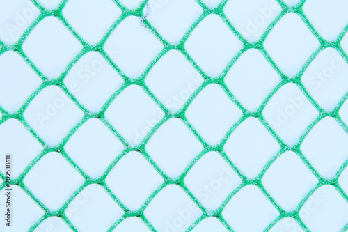 Plastic mesh covered with snow. Fence. Close-up. Background. Texture.