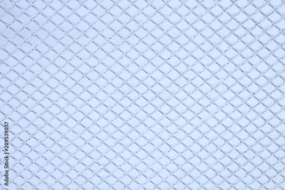 The fence of the grid is covered with snow. Close-up. Background. Texture. The fence of the grid is covered with snow. Close-up. Background. Texture.