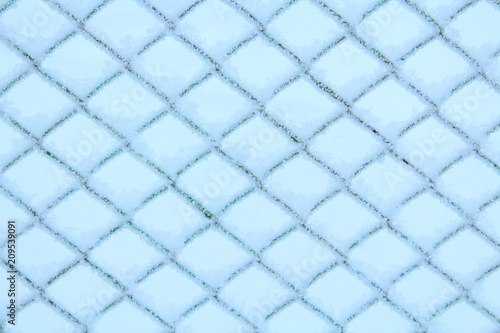 The fence of the grid is covered with snow. Close-up. Background. Texture.