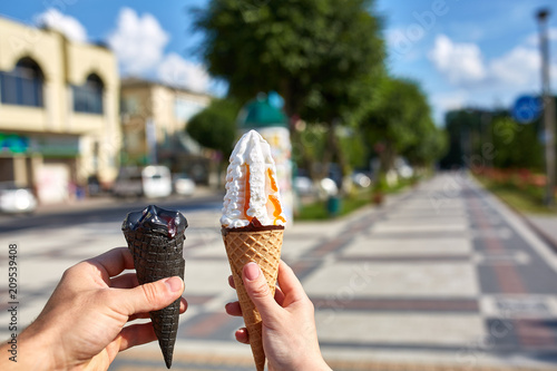 A first person view, female walking along the road with an ice cream in her hands, shallow depth of field.