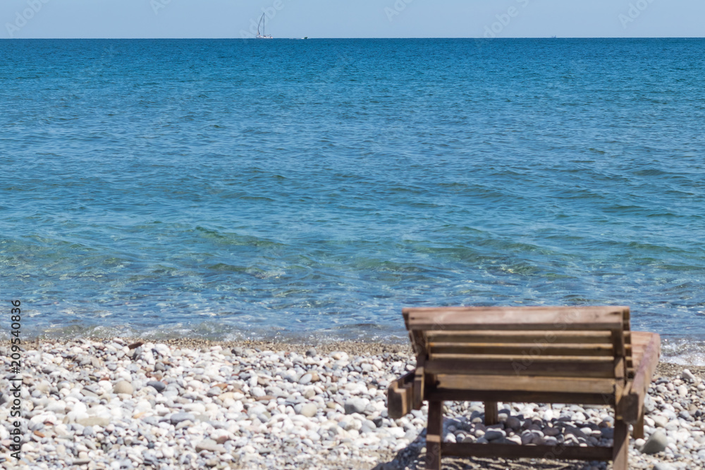 Wooden beach chair, sail on the horizon, concept summer vacation