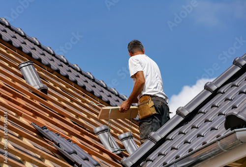 Handwerk - Dachdecker beim Eindecken eines Wohnhauses