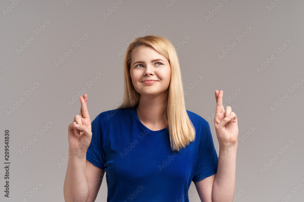 Attractive positive female model crosses fingers as hopes for better, has shining broad smile, wishes and prays for miracle Attractive positive female model crosses fingers as hopes for better, has shining broad smile, wishes and prays for miracle