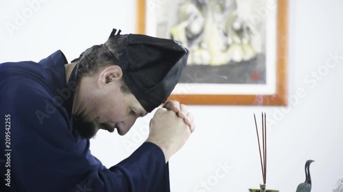 Wisdom and spirituality of Daoist meditation 4K. Long shot of spiritual male person praying to Zhang Sanfeng. Side shot tracking while bowing. Picture of Zhang Sanfeng in background. White studio. photo