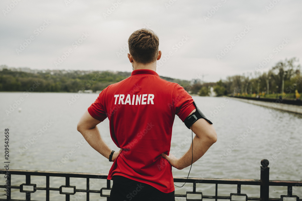 Fototapeta premium Man in trainer shirt standing on embankment