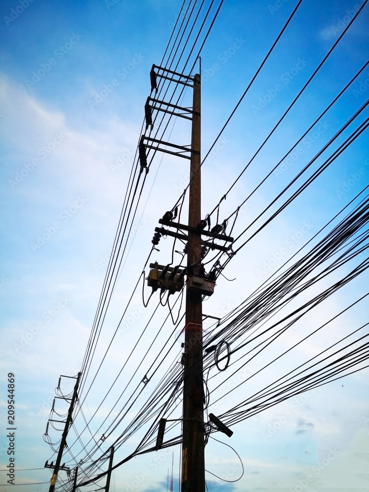 Three-phase electric poles on road side, that is common in Thailand. The electric lines, telephone lines and internet lines are within the same pole. Selective focus and copy space. Three-phase electric poles on road side, that is common in Thailand. The electric lines, telephone lines and internet lines are within the same pole. Selective focus and copy space.