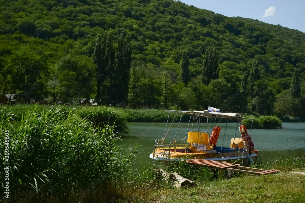 Obraz premium mountain river in the valley, around the mountains and green hills. boat near the wooden pier