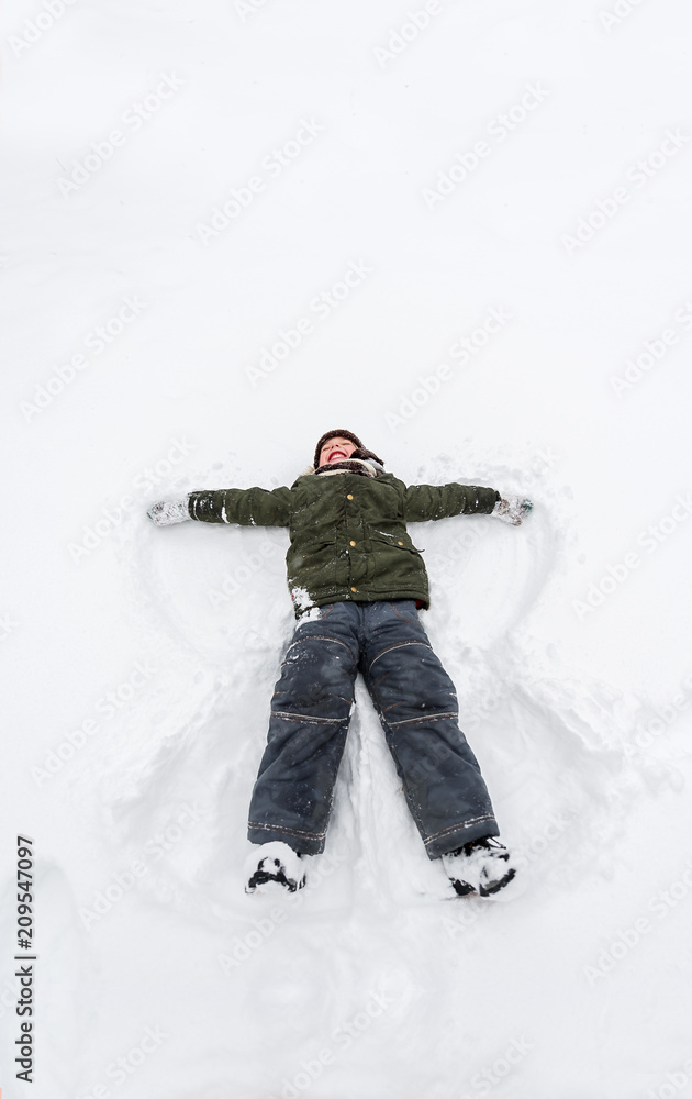 Cute little boy lie on white snow. LIttle boy having fun on winter day