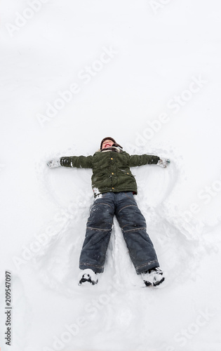 Cute little boy lie on white snow. LIttle boy having fun on winter day