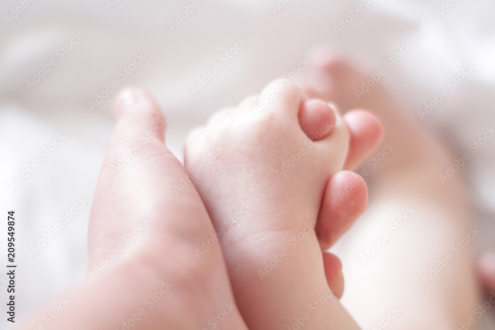 the child's hand holds the finger of an adult