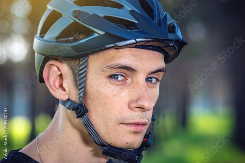 Cyclist is wearing a sports helmet on his head in the background of green nature. Protection during mountain Biking