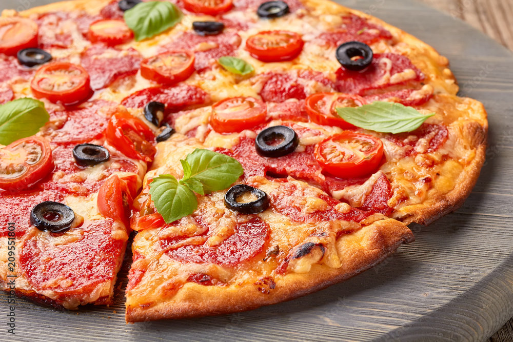 Pepperoni pizza with cherries tomatoes and olives on wooden board Pepperoni pizza with cherries tomatoes and olives on wooden board