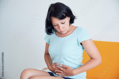Closeup ill young woman on sofa. concept suffering from abdominal pain photo