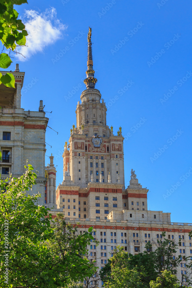 Buildings of Lomonosov Moscow State University (MSU) on a blue sky and green trees background