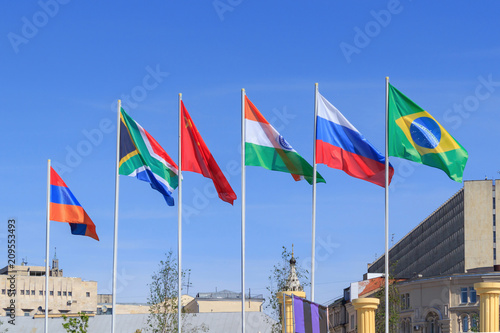 Flags of BRICS countries on a sunny summer morning against blue sky