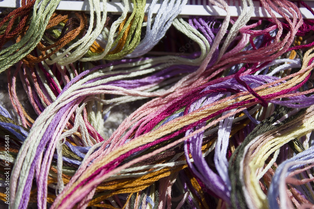 bright multi-colored floss threads in sunlight main background
