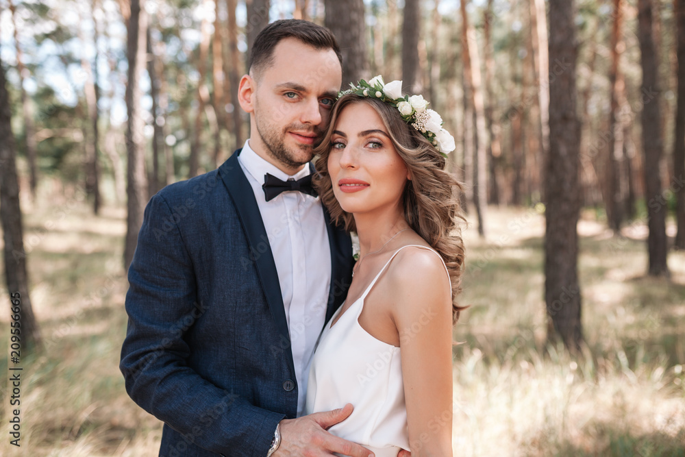 Fototapeta premium Bride and groom at wedding Day walking Outdoors on summer nature. Bridal couple, Happy Newlywed woman and man embracing in green park. Loving wedding couple outdoor. Bride and groom