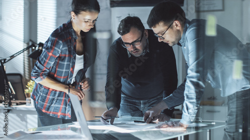 Team of Design Engineers Collectively Work on the Project. They Inspect Drafts, Documents and Have Discussion at the Big Table. photo